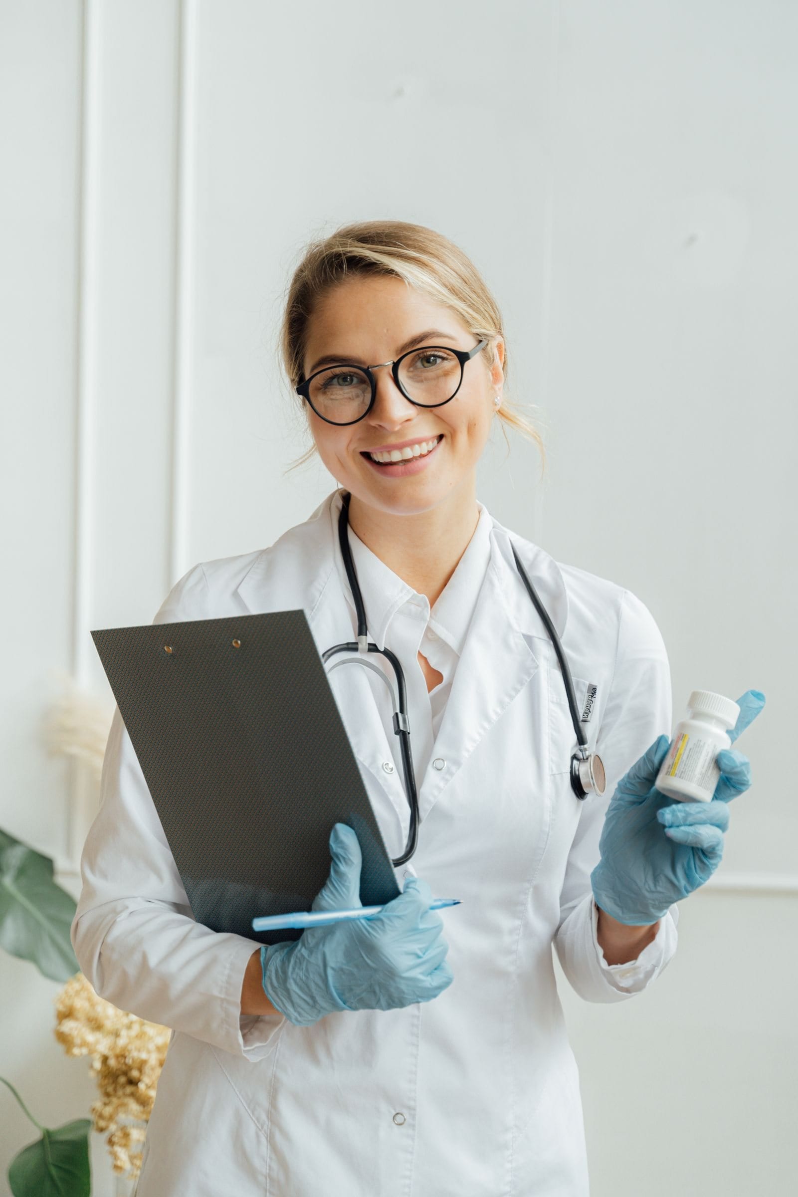 A smiling doctor in a white coat holding a clipboard