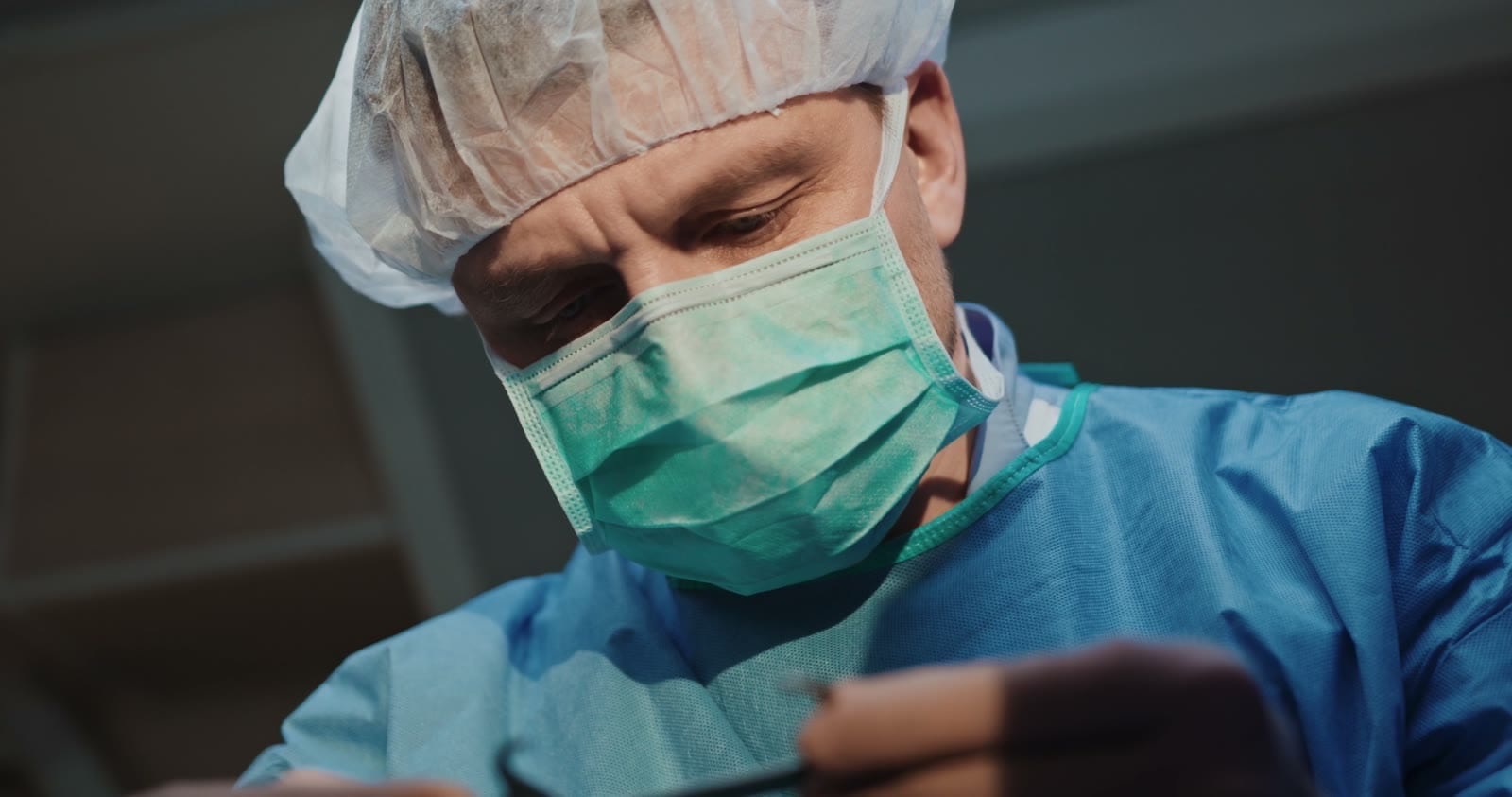 A physician in surgical scrubs concentrating on their work